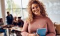 Portrait of happy female student at college classroom looking at camera.